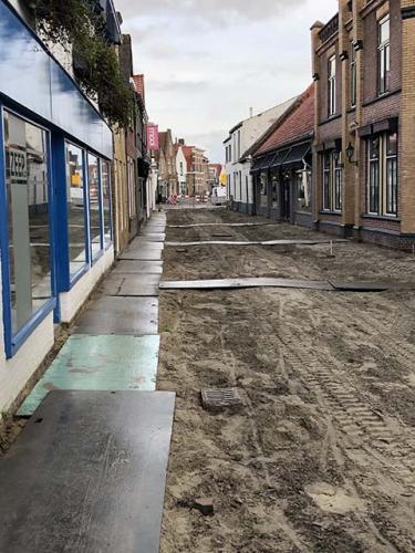 nieuwstraat, zandbed waaruit de straatstenen zijn verwijderd, met rijplaten voor voetgangers langs de gevels